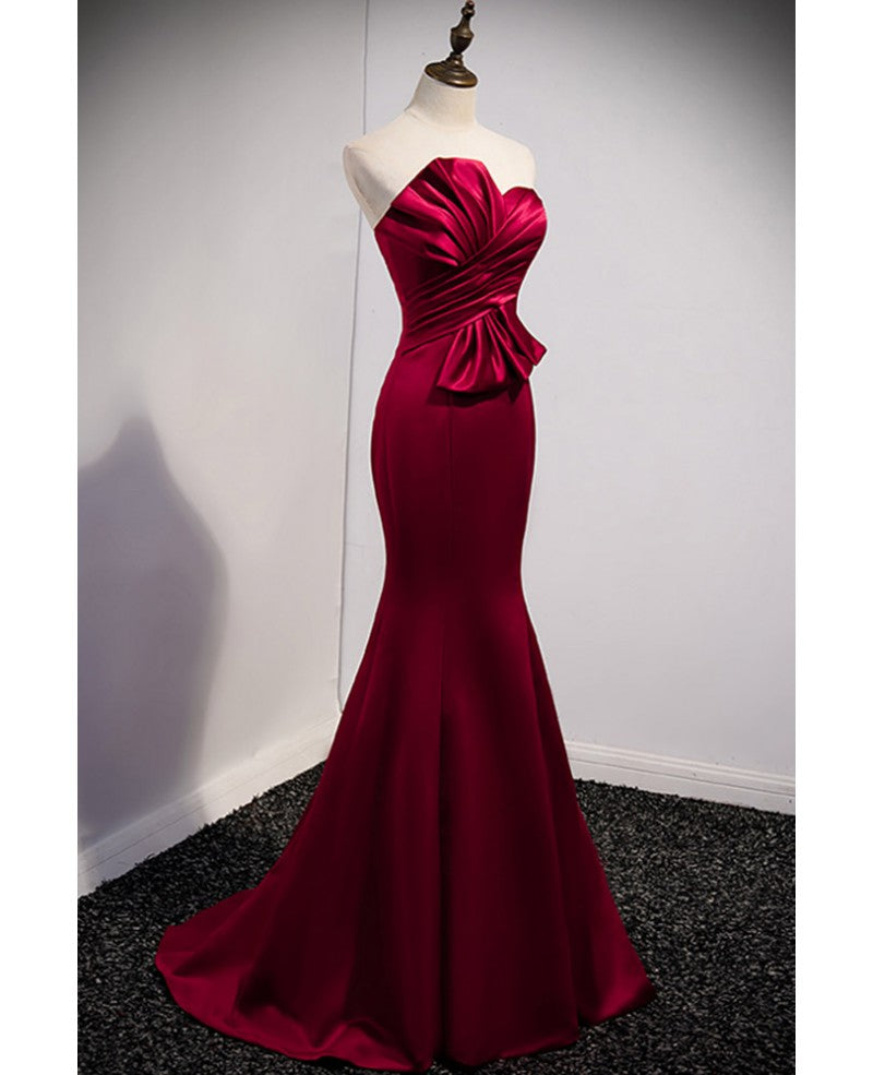 Un abito da ballo rosso vino nobile e minimalista, senza maniche, con spalle scoperte, spalline senza spalline e schiena color rosso vino e abito da sera a sirena lungo fino a terra.